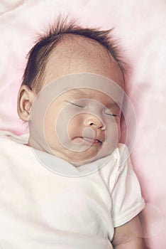 Peaceful baby lying on a bed while sleeping in a bright room