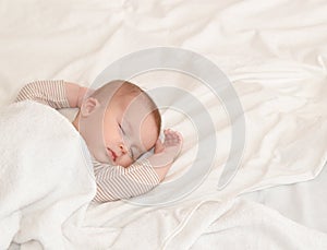 Peaceful baby lying on a bed while sleeping in a bright room