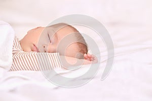 Peaceful baby lying on a bed while sleeping in a bright room