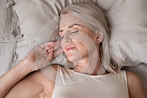 Peaceful beautiful mature woman sleeping in bed close up