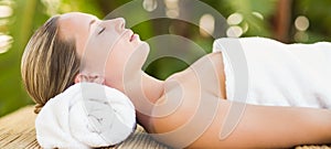 Peaceful blonde lying on bamboo mat with flowers