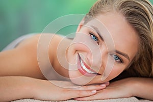 Peaceful blonde lying on towel smiling at camera