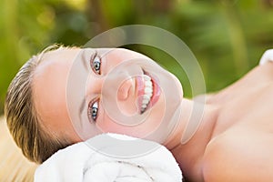 Peaceful blonde lying on towel smiling at camera