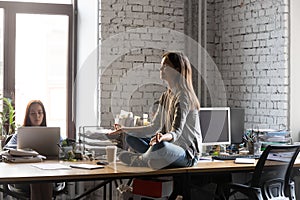 Peaceful businesswoman meditating on office desk, stress relief concept