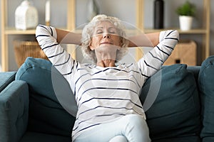 Peaceful calm older woman leaning back on couch