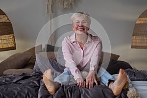 Peaceful calm positive middle aged senior retired woman sitting in bed