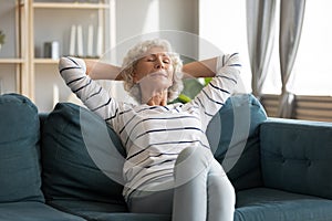 Peaceful calm retired woman relaxing om comfortable sofa.