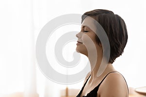 Peaceful calm young woman taking deep breath of fresh air