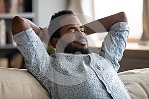 Peaceful carefree biracial guy alone napping on couch indoors.