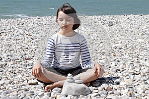 Peaceful child sitting with pebbles for mindfulness and ocean energy