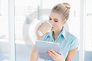 Peaceful classy woman using tablet while drinking coffee