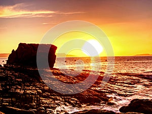 Peaceful dawn at Elgol bay. Low angle overlooking of offshore rocks and smooth sea, mountains