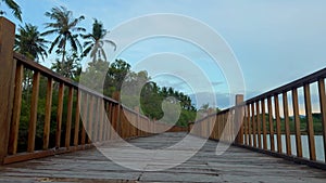 Peaceful dock with footbridge in tropical paradise. Beautiful island at blue twilight and old wooden pier. Long bridge