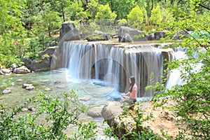 Peaceful happy life, careless Asian Chinese woman do yoga before waterfall