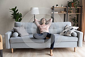 Peaceful happy young woman relaxing on comfortable sofa.
