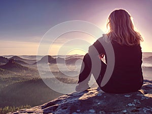 Peaceful landscape. pretty girl sit on rocks, look far away photo