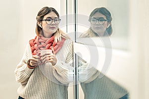 Peaceful long-haired girl in wireless headphones looking outside the window