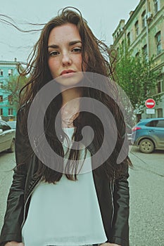 Peaceful looking girl posing with windy hair ouside, wide angle smartphone lens imitation vertical image