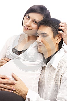 Peaceful Lovely Dreaming Caucasian Couple with Pregnant Woman While Sitting Embraced Over White Background