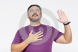 A peaceful man in a purple shirt with a raised hand exudes tranquility and calmness, illustrating a moment of silence or