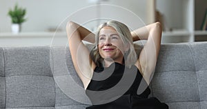 Peaceful middle-aged pretty woman relaxing leaned on sofa