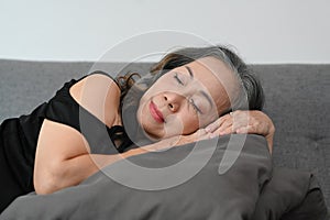 Peaceful middle aged woman resting, sleeping or taking nap on comfortable couch at home