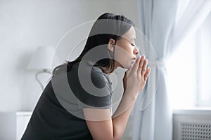 Peaceful mixed raced girl with closed eyes praying to god