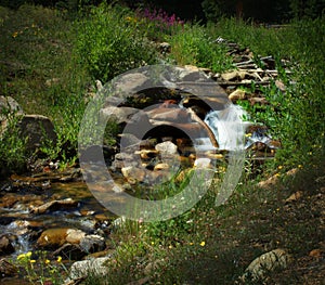 Peaceful mountain stream / brook with a cascade of water tumbling over rocks, flowing into the foreground of the picture.