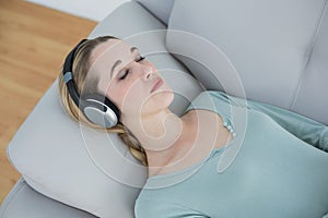 Peaceful natural woman listening to music while lying on couch