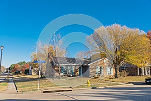 Peaceful neighborhood street with residential house and autumn leaves in suburban subdivision near Dallas, Texas, USA