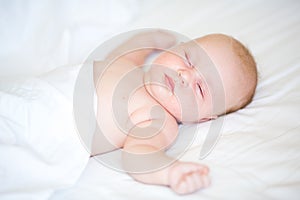 Peaceful newborn baby lying on a bed sleeping