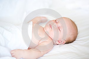 Peaceful newborn baby lying on a bed sleeping