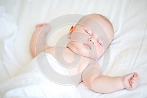 Peaceful newborn baby lying on a bed sleeping