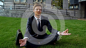 Peaceful office worker meditating after day in office, sitting in lotus position