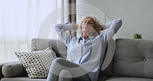 Peaceful older mature lady relaxing on cozy couch.