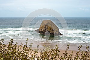 A peaceful Oregon beach coastline with Jockey Cap Rock in the middle, crashing ocean waves. Nature Landscape Background. Island ne