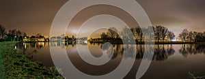 Peaceful panoramic view of river and trees backlit by Amsterdam city lights