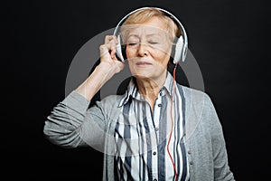 Peaceful pensioner enjoying music in the black colored studio
