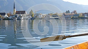 A peaceful picture a wooden boat with an oar floats on beautiful mountain lake Tegernsee against backdrop of Alpine