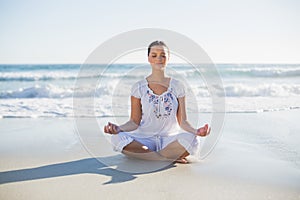 Peaceful pretty woman in lotus position on the beach