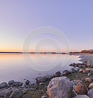 Peaceful, quiet and remote landscape view of the beach and sea water during sunset in summer. Beautiful, calm and scenic