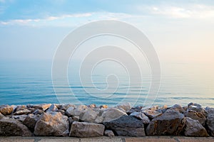 Peaceful quiet rock pier at sunrise with calm blue sea waves