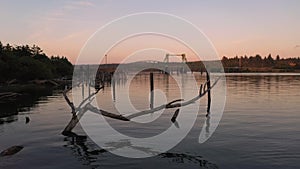 Peaceful river scene in Oregon with cars traveling across bridge in background.