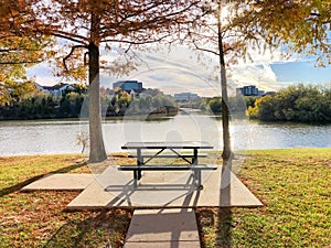 Peaceful riverside picnic table and corporate building offices along Trinity River near Dallas, Texas, America