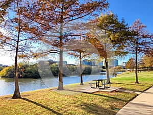 Peaceful riverside picnic table and corporate building offices along Trinity River near Dallas, Texas, America