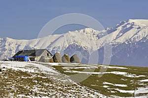 Peaceful rural landscape with traditional Romanian mountainous farm with old barn and haystacks, near Bucegi massif