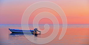 A peaceful sea with warm sunset colors and a solitary boat in a beach near Agrigento in Sicily Italy