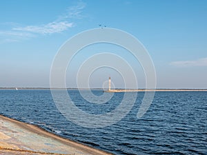 Peaceful seascape with blue Kyiv Cistern, birds above the lighthouse and yacht