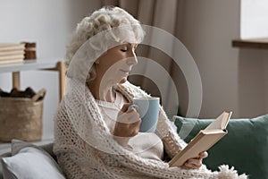 Peaceful senior retired woman wrapped in knitted plaid