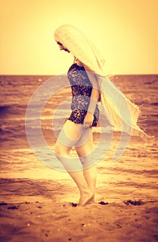 Peaceful sensual woman walking on beach sand